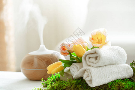 带有现代精油扩散器香气的水疗组合物和身体护理产品扭曲的白毛巾春天的绿色和鲜花身体和保背景图片