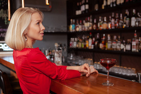 一个华丽优雅的金发女郎在酒吧穿着红色连衣裙的侧面照片图片