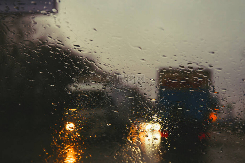 通过汽车挡风玻璃上的雨滴看到城市道路图片