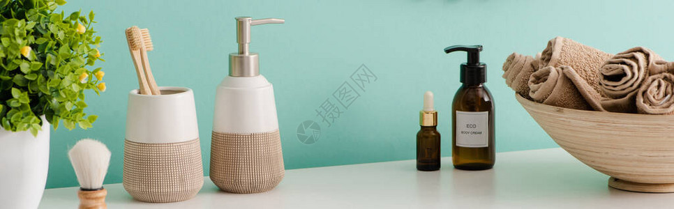 在浴室有毛巾的碗旁看到花盆化妆品和卫生用品的全景图片