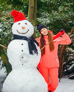 妇女穿着红色帽子和手套用雪图片