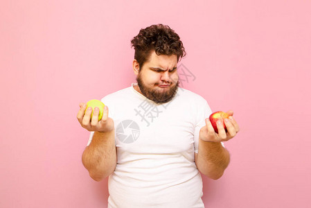 滑稽的胖男人留着胡子看着手中的苹果图片