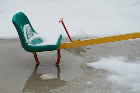 孩子们在操场玩耍时的融雪绿色秋千座位图片