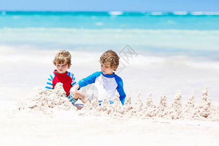 两个小男孩在马尔代夫热带海滩上兴建沙堡玩得开心图片