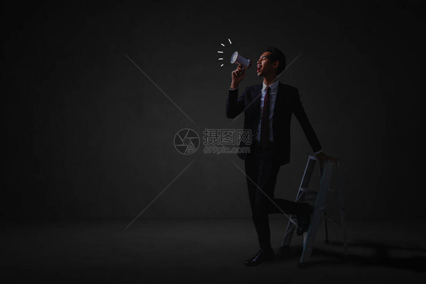 商人站立用扩音器向黑暗房图片