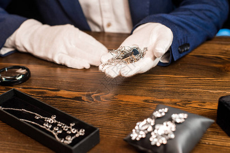 珠宝估价员将珠宝放在黑色背景桌子上放大玻璃附近图片