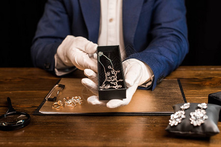 珠宝估价员拿着一盒装有项链的珠宝鉴定人被切碎的视图图片