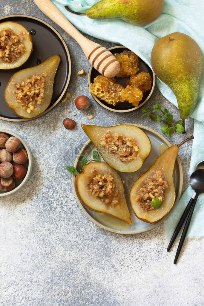 健康饮食甜点在石板石头或混凝土背景上用榛子蜂蜜和格兰诺拉麦片烤梨顶视图平躺背图片