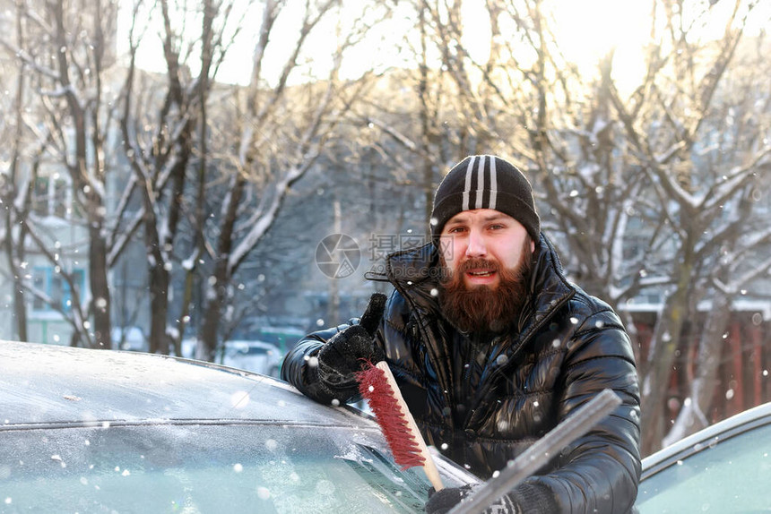 男人在车上擦玻璃上的雪图片