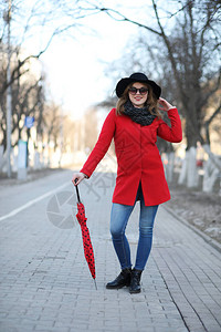 漂亮的女孩带着红伞在城市里散步图片