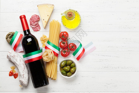 意大利菜食品配料意大利面奶酪意大利腊肠橄榄和葡萄酒顶视图平铺在木桌上图片