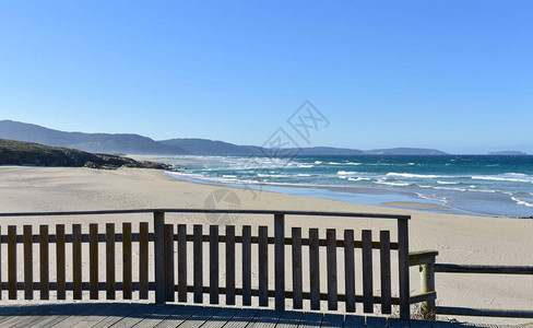 有木板路和扶手的海滩与波浪和蓝天的狂放的海Arteixo图片