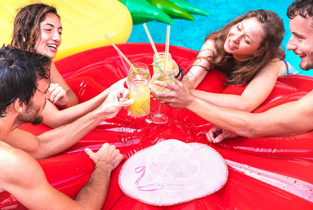 年轻人在泳池派对上喝水果鸡尾酒的剪影豪华度假概念图片