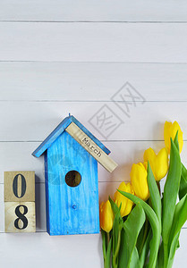 月8日木块日历上的文字黄色郁金香和粉红色背景上的亮蓝色鸟舍图片为包裹春天的心情母亲节妇女节的春背景图片