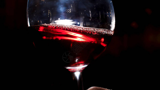用手摇晃红酒杯一位侍酒师的特写是在深色背景中摇晃酒杯图片