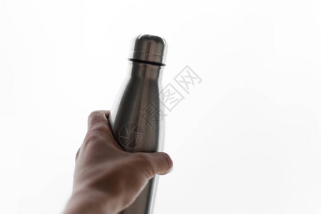 不锈钢热水瓶在白色背景上孤立的人手中图片
