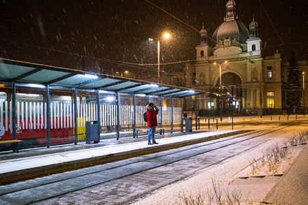 身穿红色冬衣的男子站在公共汽车电站等待公共交通火车站在图片