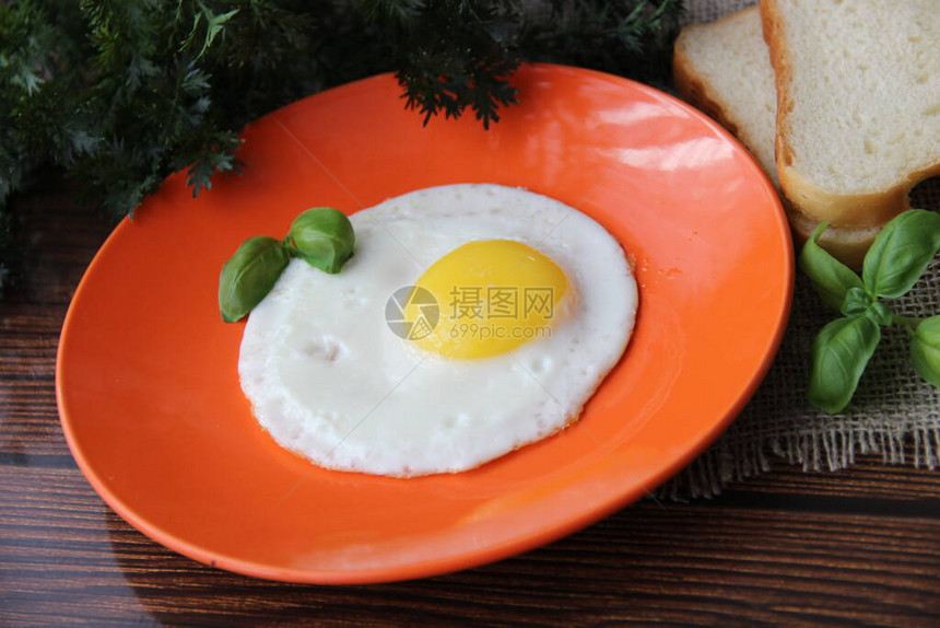 烤鸡蛋和Basil在橙色盘子上图片