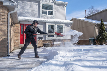 男子在屋前用红铲除雪图片