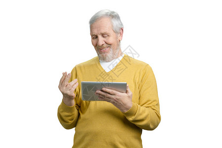 老爷在平板网络摄像头上进行视频对话笑着高兴的老人穿黄色毛衣图片