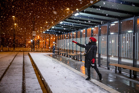 女人看着雪在电车站着图片
