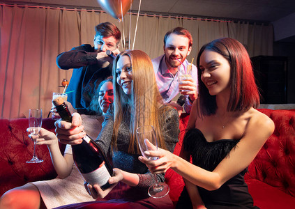 参加卡拉OK酒吧晚会喝香槟和用麦克风唱歌的年青天主教青年聚集一堂图片