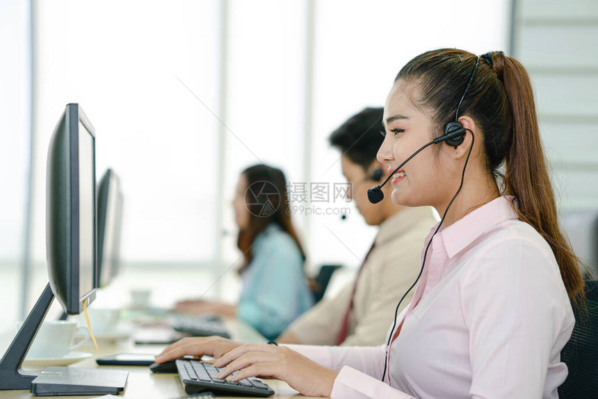 呼叫中心工作人员由她的团队陪同微笑的客户支持操作员在工作使用耳图片