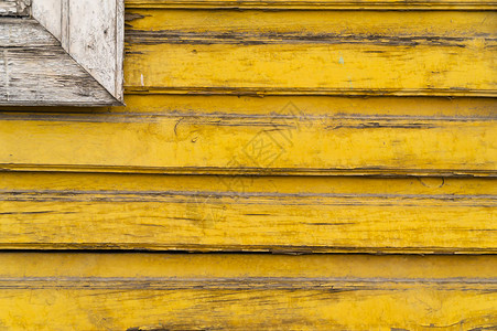 旧的黄色木墙与破裂的油漆层水平的黄色木板与白色方形详细的图片