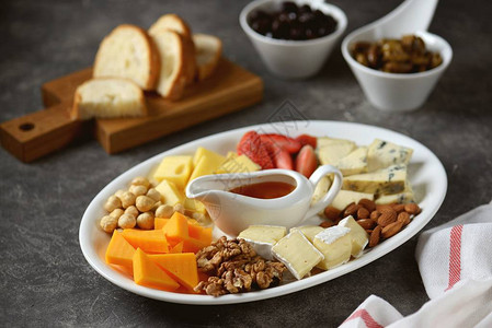 各种带橄榄坚果水果和蜂蜜的奶酪背景图片