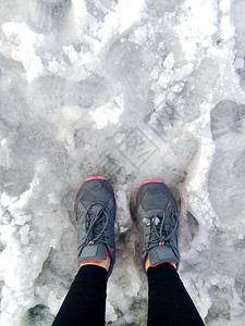 穿着运动鞋的双腿在湿雪上站着登山图片