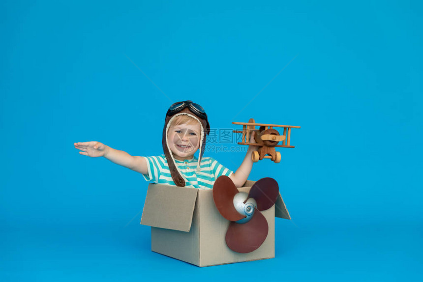 快乐的孩子梦想成为一名飞行员孩子在蓝皮书背景下玩得开心男孩穿着条纹衬衫在纸箱里玩耍暑假和旅游概念图片