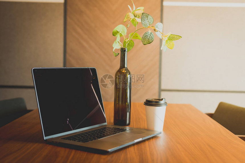 手持笔记本电脑和拿起桌上咖啡的杯子生活方式概念图片