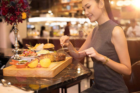 工作的亚洲女人黑头发午餐大块牛排烧烤晚餐在融合餐厅咖啡厅吃西餐背景图片