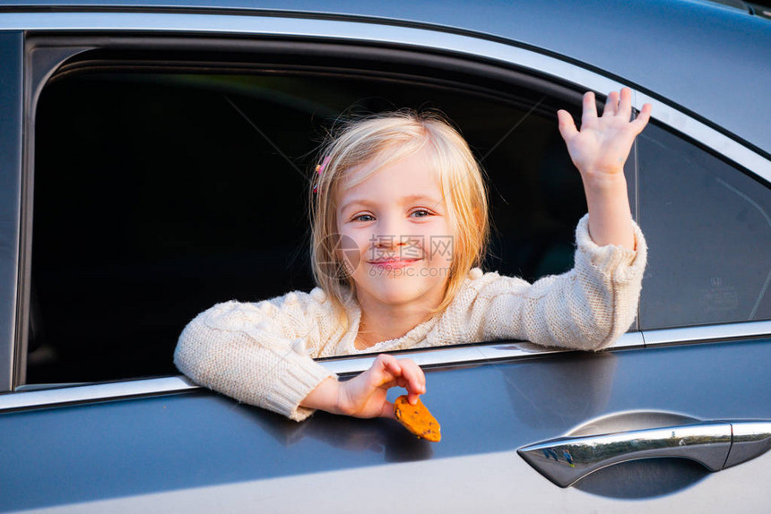 一个小女孩正把头探出车窗公路旅行或旅行概念快乐的孩子们乘车旅行可爱的孩子从面包车窗外探出头来图片