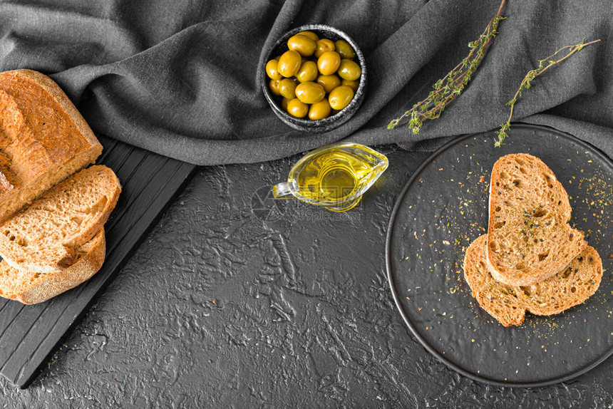深色背景中带面包的美味橄榄油图片