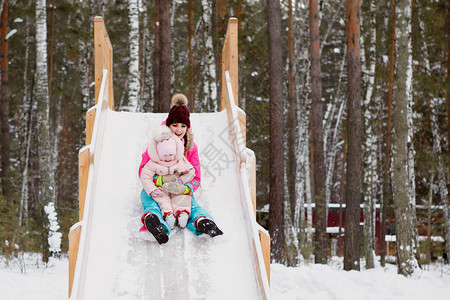 有女儿的女人在雪天滑下一个冰冷的木头山冬季俄罗斯欢乐亮衣服图片