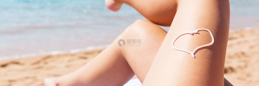 在海边毛巾上晒太阳时女腿部的日光浴以心的形图片
