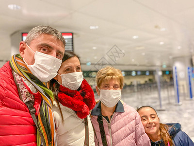 冠状Covid19正在意大利和欧洲蔓延机场的多代家庭戴着防护面罩以避图片