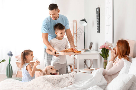 快乐的丈夫带着孩子带妻子在床上吃早图片