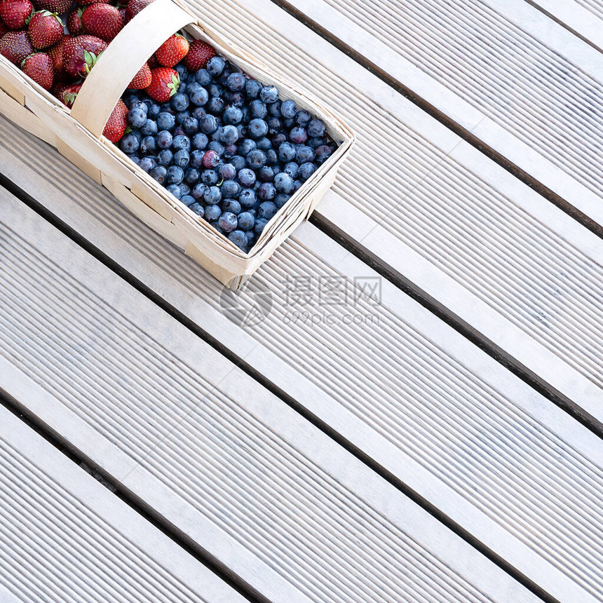 草莓和蓝莓的新鲜浆果放在阳台露板上的篮子里食品概念平面布局园艺夏图片