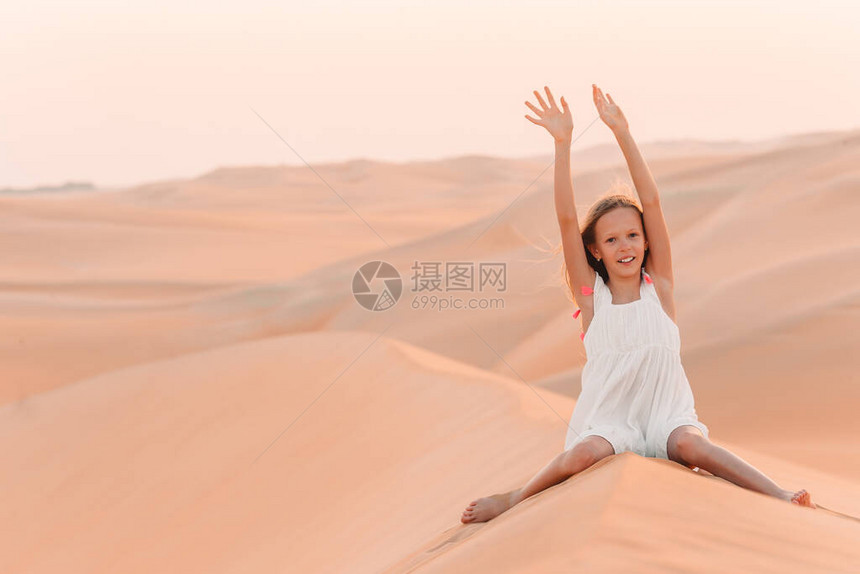 女孩在沙丘的真正沙漠中玩得开心图片