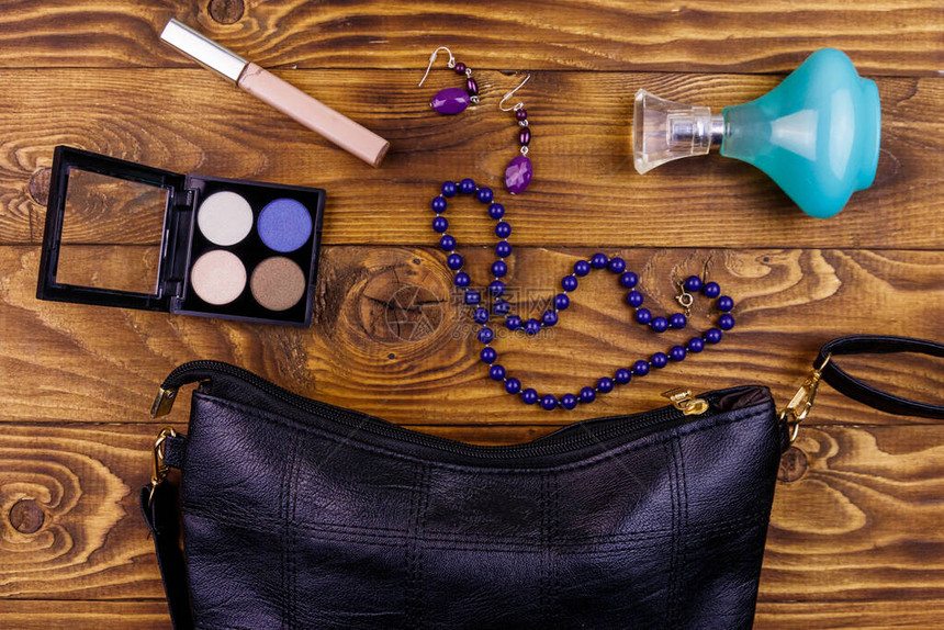 木制背景上的女配饰木桌上的手拿包香水瓶眼影项链和耳环美容和时尚组成图片