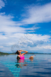 与成人混合种族晒黑瘦女人在感的粉红色比基尼泳装的边池在夏日岛度假图片