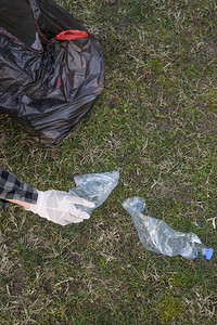 从公园捡塑料瓶的女人人士收集塑料垃圾的照片志愿者在户外捡起一图片