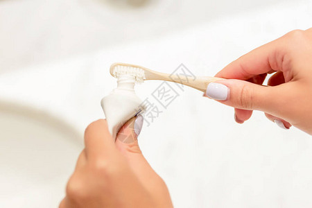 女手把牙膏放在浴室里的牙刷上的裁剪图像牙科护理概图片