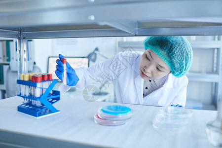 横向中近拍亚洲年轻女实验室工人用试管标本取出试管的背景图片