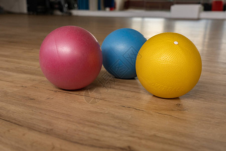 团体健身中心体操馆木地板上的三个小而多彩的体操球背景中镜子的倒影低角图片