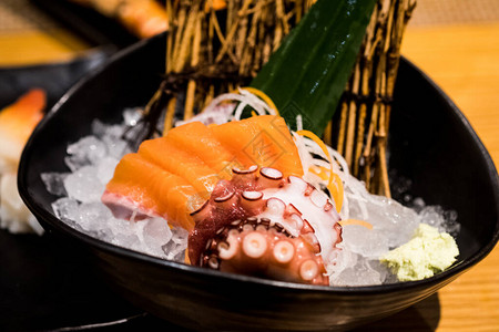 三文鱼生片和章鱼生片放在黑碗的冰上日本食品图片