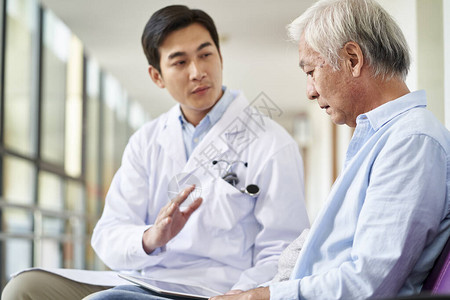 年轻的亚洲医生在医院走廊向士气低落的老年患者谈话和解释测图片