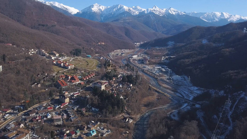 在风景如画的阳光明媚的阿尔卑斯山附近的山谷中鸟瞰冬季奥地利村庄飞越被高山森林环绕的乡图片